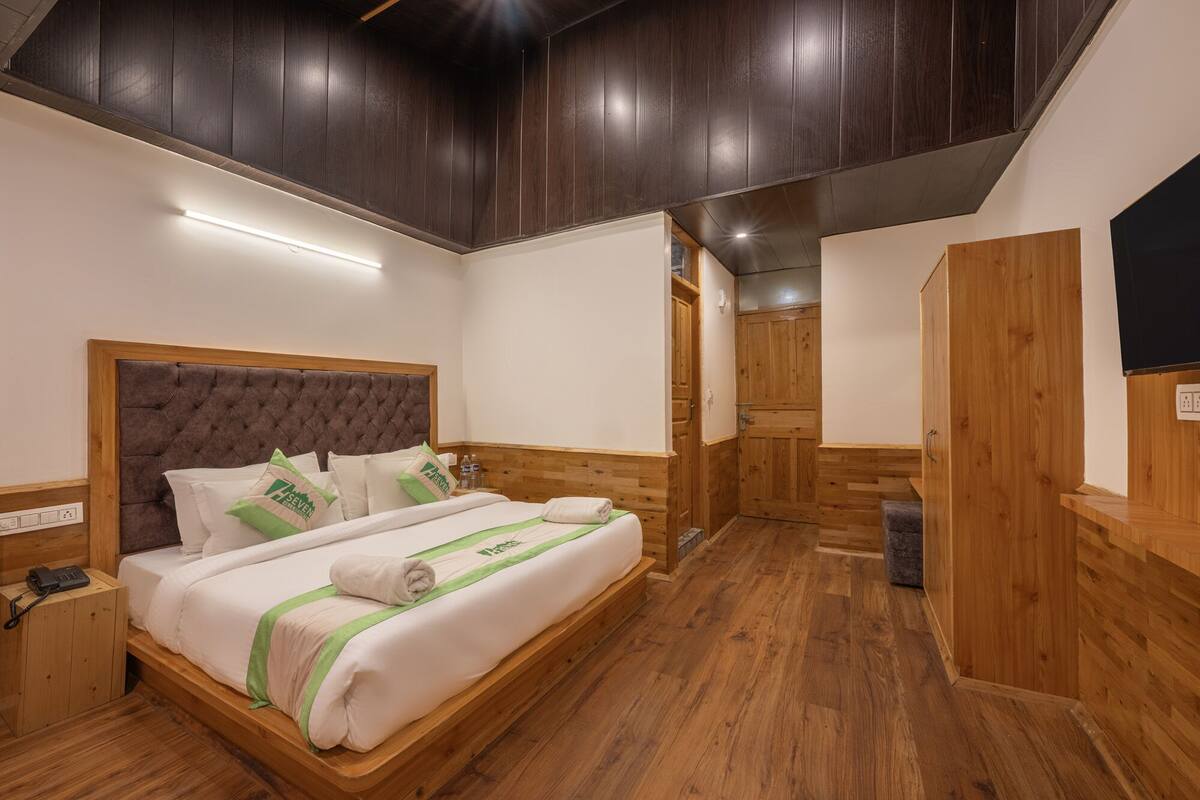 Habitación de hotel con cama, armario y suelo de madera.