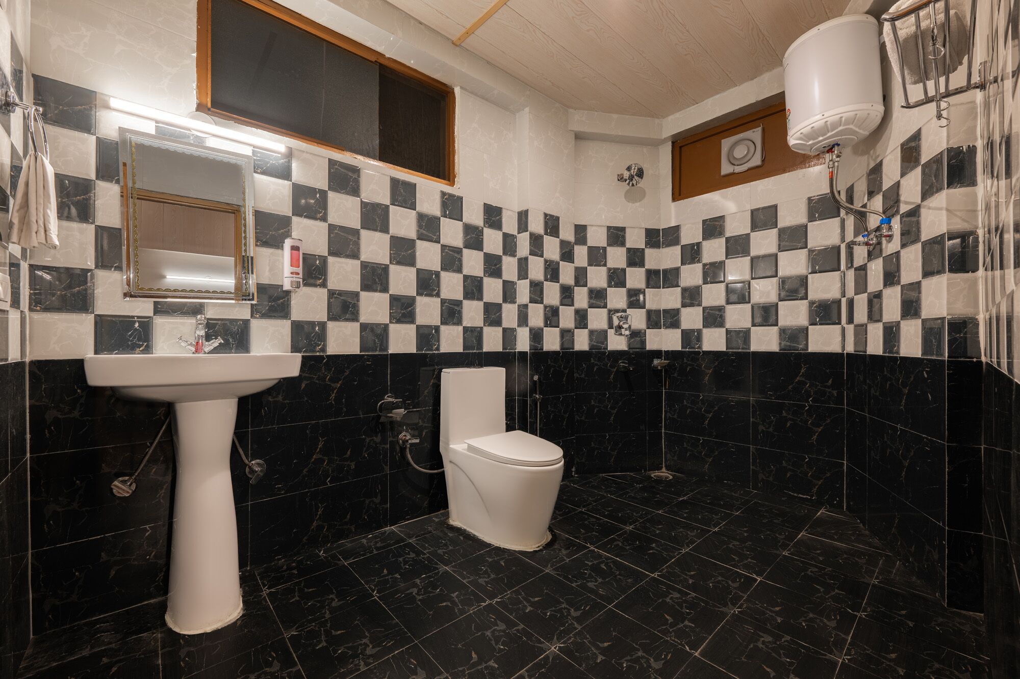 A bathroom with a checkered tile backsplash, a white sink, a toilet, and a shower area.