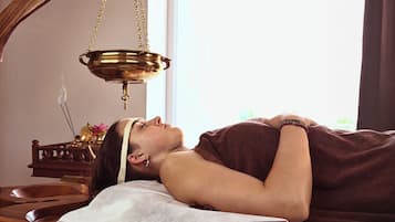 Guests can unwind in a serene spa setting with a treatment table, brass oil burner, and peaceful ambiance.