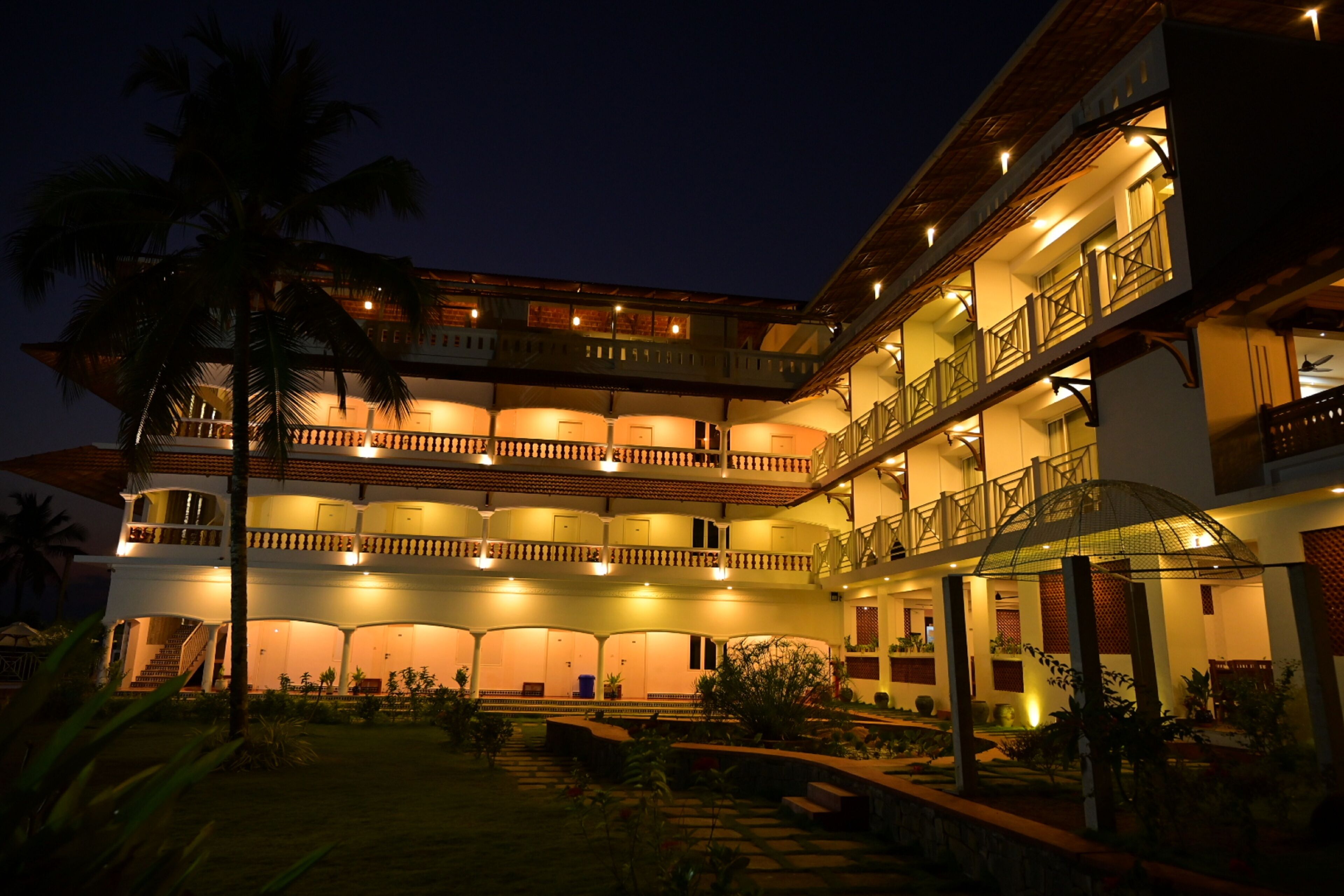 A multi-story hotel with a central courtyard, balconies, and a well-lit facade.