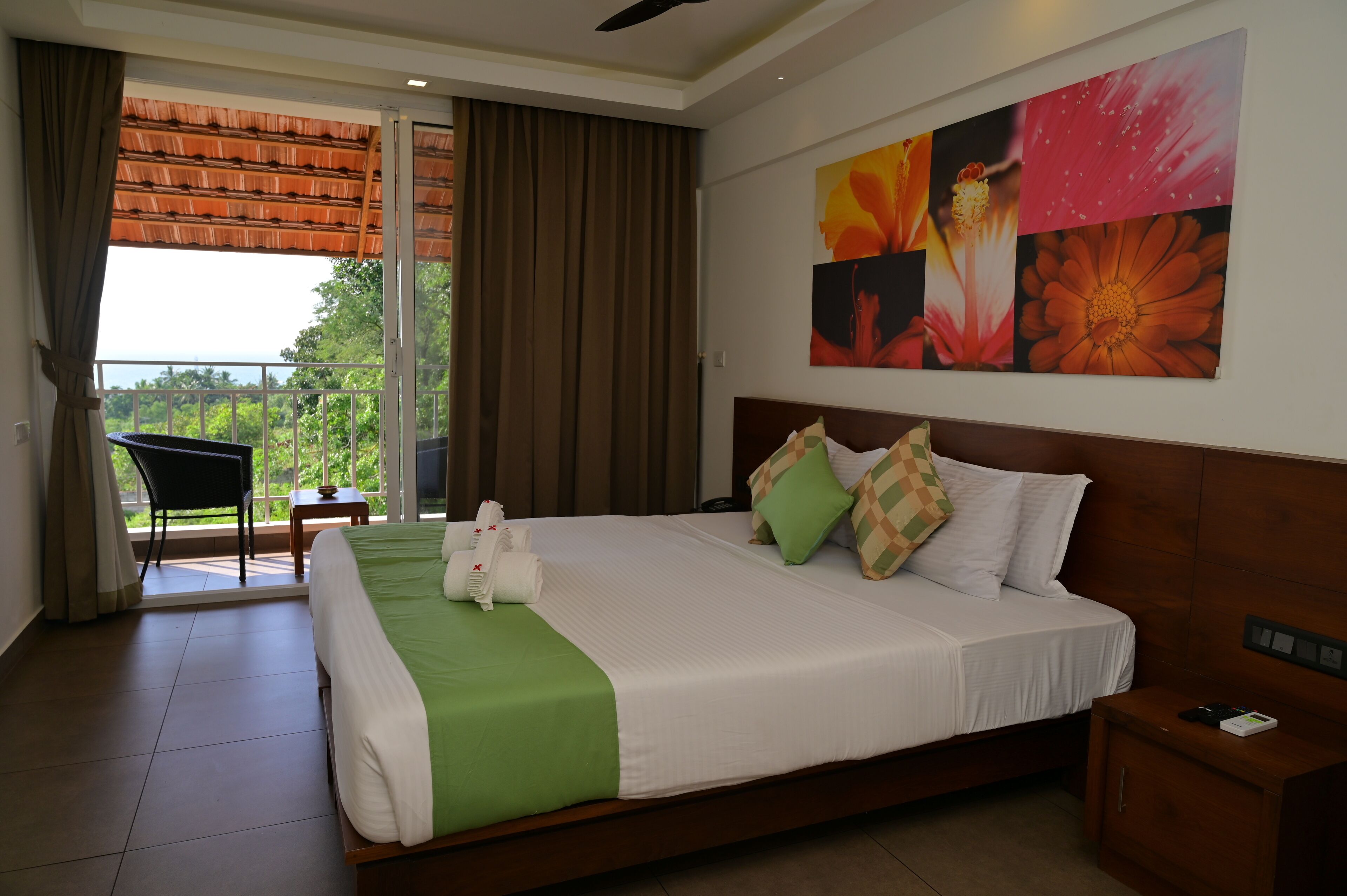 A hotel room with a bed, a chair, a table, and a balcony with curtains.