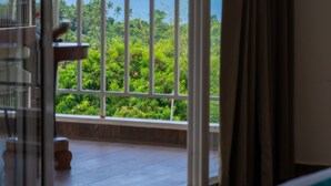 Ein Zimmer mit einer großen Glasdoor, die auf einen Balkon mit Blick auf das Meer und das Grün führt.