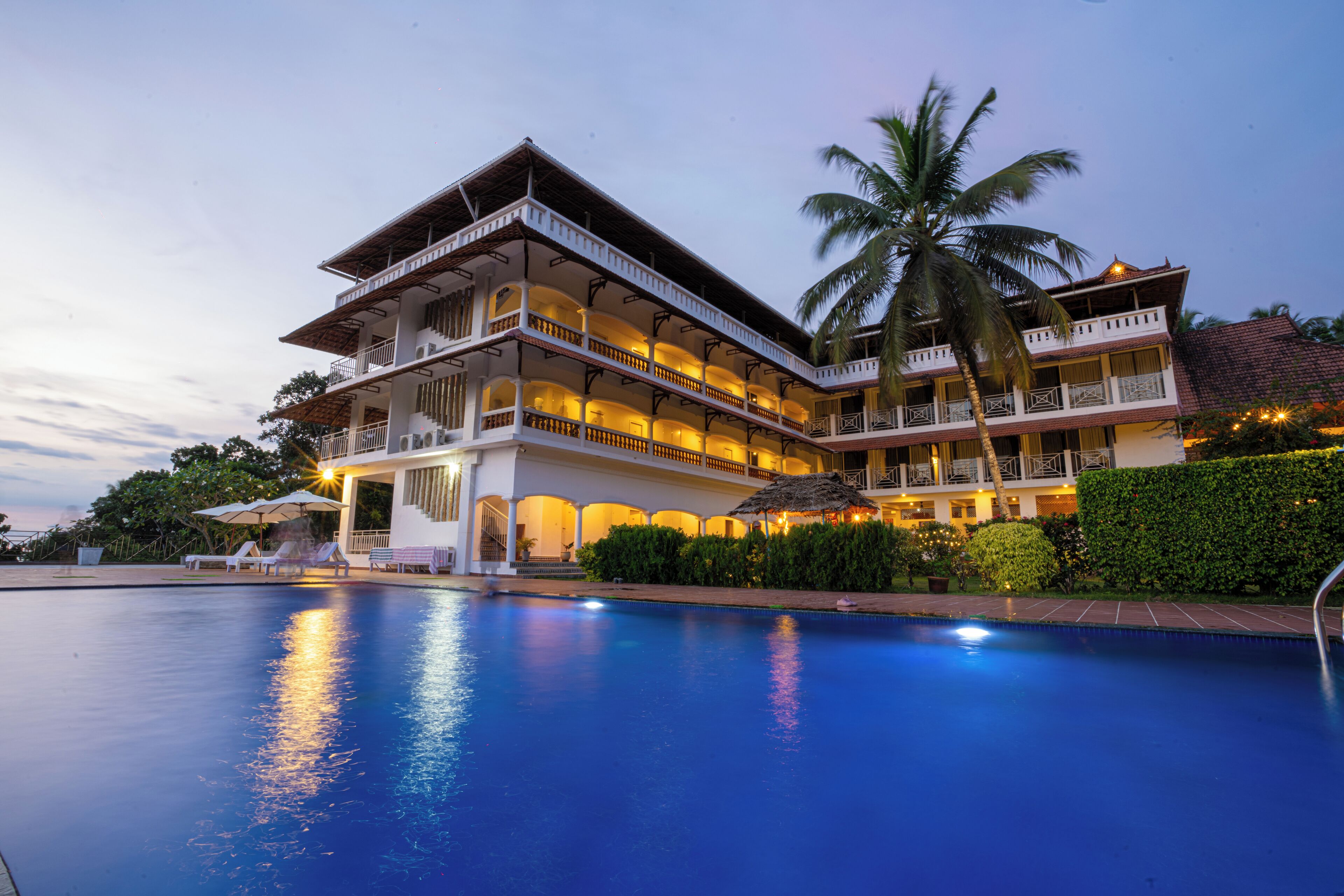 Um hotel grande, com vários andares e uma piscina em primeiro plano.