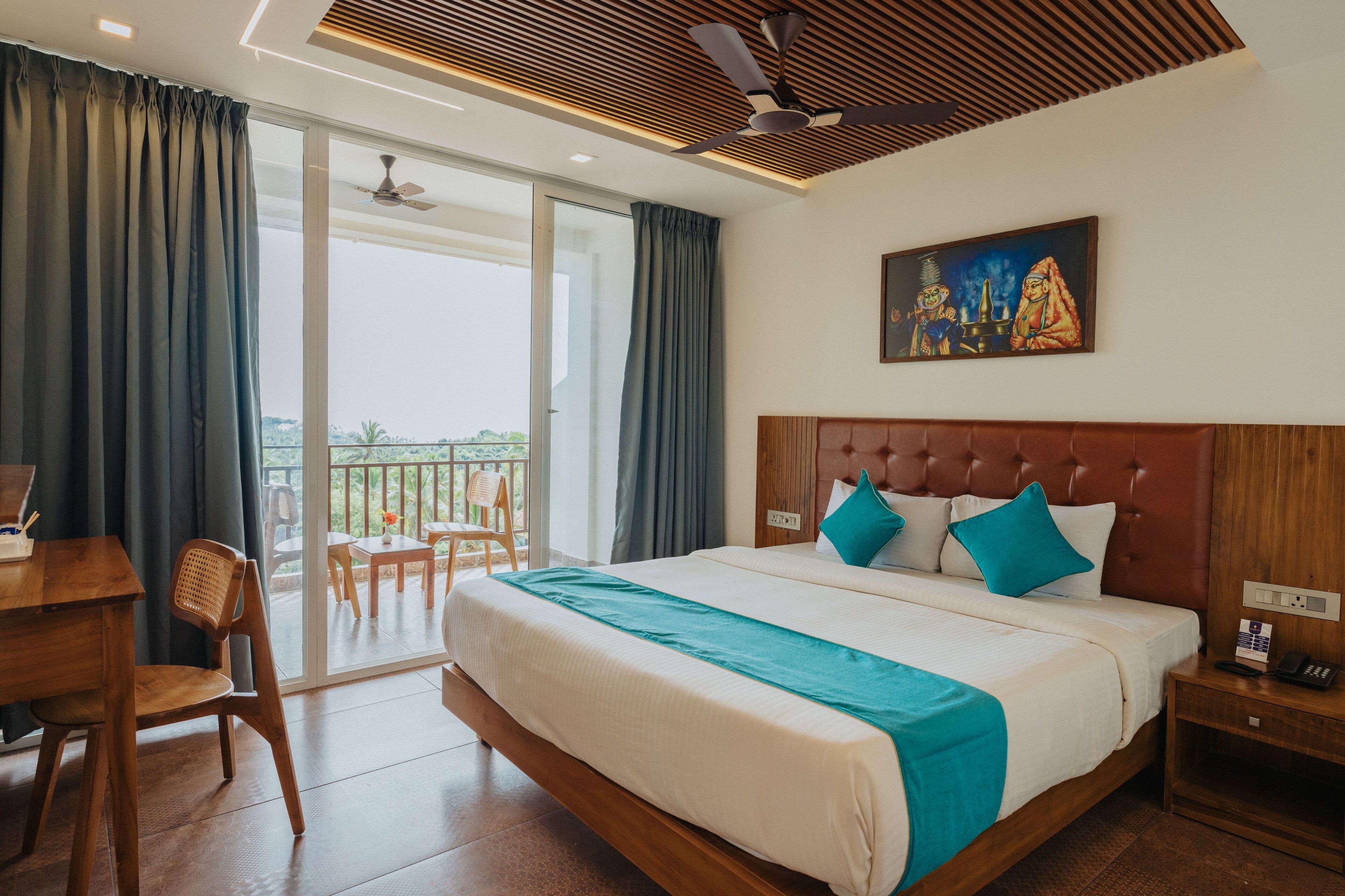 A hotel room with a large bed, a desk, and a balcony with a view.