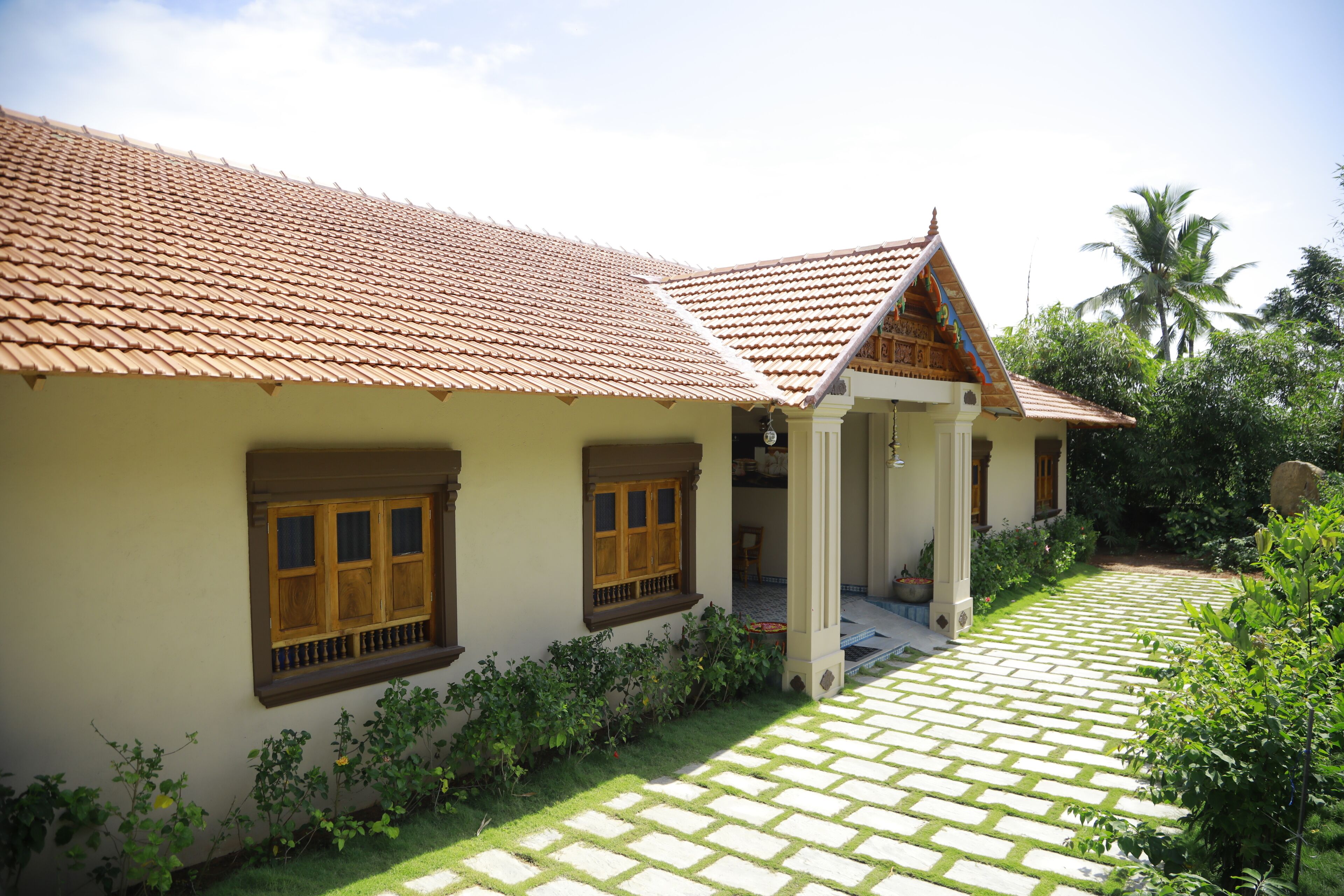 Une maison traditionnelle avec un toit en tuiles, une cour pavée et une végétation luxuriante.