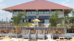 Un club de plage avec un toit rouge et un espace extérieur aménagé avec des sièges.