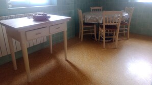 Un pequeño comedor con mesa y sillas, ventana y salpicadero de azulejos.