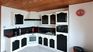 A kitchen with white and black cabinets, a microwave, a sink, and a red trash bin. - Peaceful house in the heart of Alsace (Baldenheim)