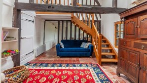 Una habitación con un sofá azul, una escalera de madera y un tapete rojo estampado.