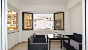 A balcony with a view of buildings, a table, and two chairs.