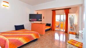 A hotel room with a bed, a TV, a desk, and a balcony with orange curtains. - Apartment 2222/67254 (Istria - Pula), 500m from the beach (Pula)