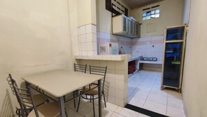 Uma cozinha compacta com uma mesa de jantar e cadeiras, geladeira e micro-ondas.