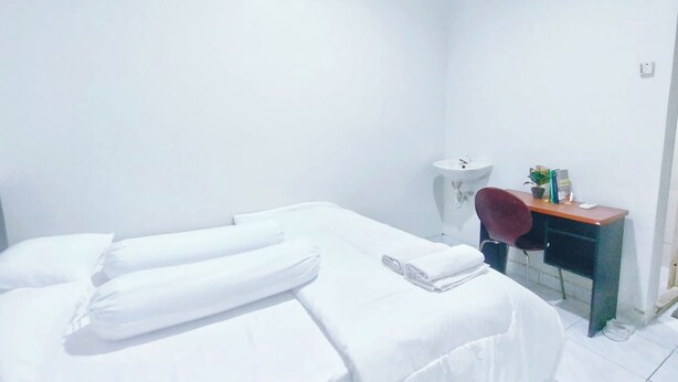 Quarto de hotel com cama, escrivaninha, cadeira, pia e ar condicionado.