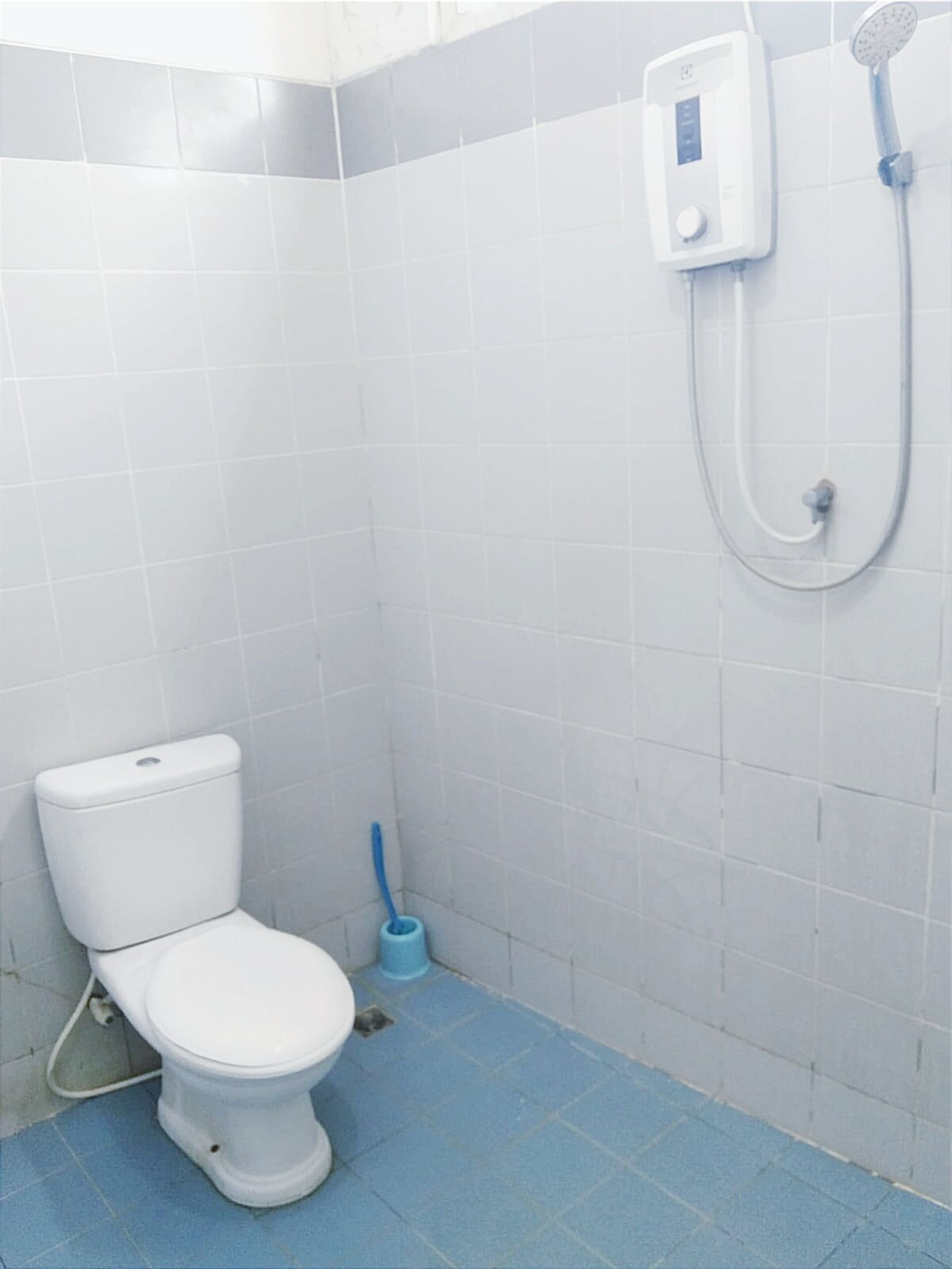 A small, clean bathroom with a toilet, a shower, and a blue floor.