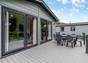 A modern house with a deck, sliding glass doors, and outdoor furniture.