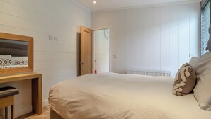Un dormitorio con cama, mesita de noche, espejo y ventana con persianas.
