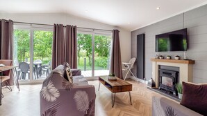 Una sala de estar moderna con un sofá, una mesa de centro, una chimenea y un televisor montado en la pared.