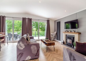 A modern living room with a sofa, a coffee table, a fireplace, and a TV mounted on the wall.