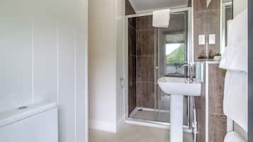 A modern bathroom with a glass shower enclosure, a white sink, and a mirror with a towel.