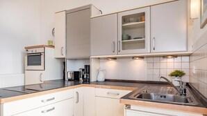 Eine moderne Küche mit weißen Schränken, einem Backofen, einer Kaffeemaschine und einem Spülbecken mit Armatur.