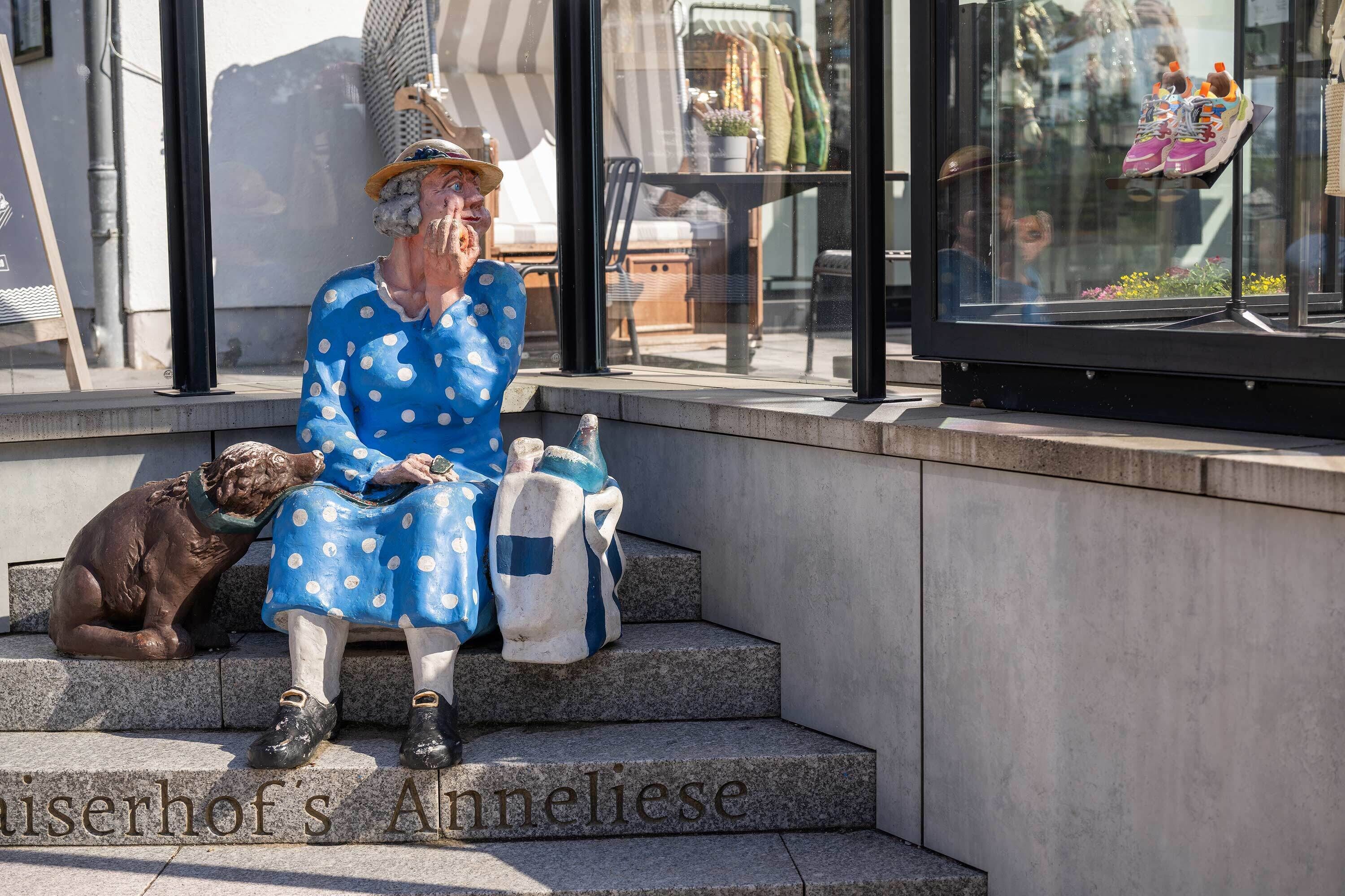 A statue of a woman in a polka dot dress sitting on steps with a dog beside her.