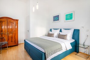 A bedroom with a bed, a wardrobe, a chair, and two wall-mounted lights.