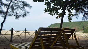 A beach with wooden lounge chairs and a fence.