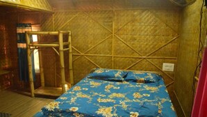 A room with a bed, a wooden chair, and a bamboo wall structure.