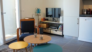 Ein kompakter Wohnbereich mit Fernseher, Küchenzeile und Sitzecke.