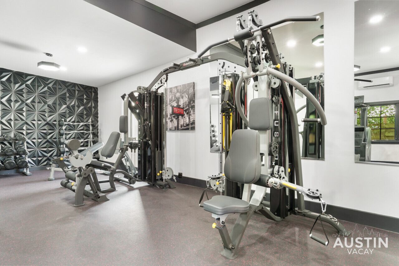 A modern gym with various exercise machines, a wall with geometric patterns, and a large mirror.