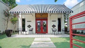 A building with a red door, two lounge signs, and a striped awning. - Amenity Heavy Serene Apt in Convenient Location (Austin)