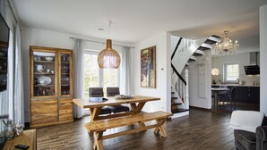 A spacious living area with a wooden dining table, bench, and a staircase leading to an upper level. - House in idyllic location with sauna, terrace and garden - Villa Morgensünn (Vaschwitz)
