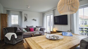 A modern living room with a grey sofa, wooden coffee table, and a large window. - House in idyllic location with sauna, terrace and garden - Villa Morgensünn (Vaschwitz)