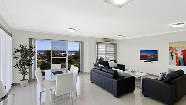 A modern living room with a balcony, a dining area, and a sofa set.