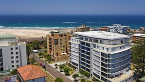A coastal urban area with modern buildings, a beach, and a clear view of the ocean.