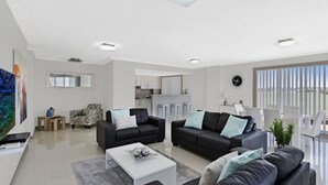 A modern living room with two sofas, a coffee table, and a kitchen area in the background.