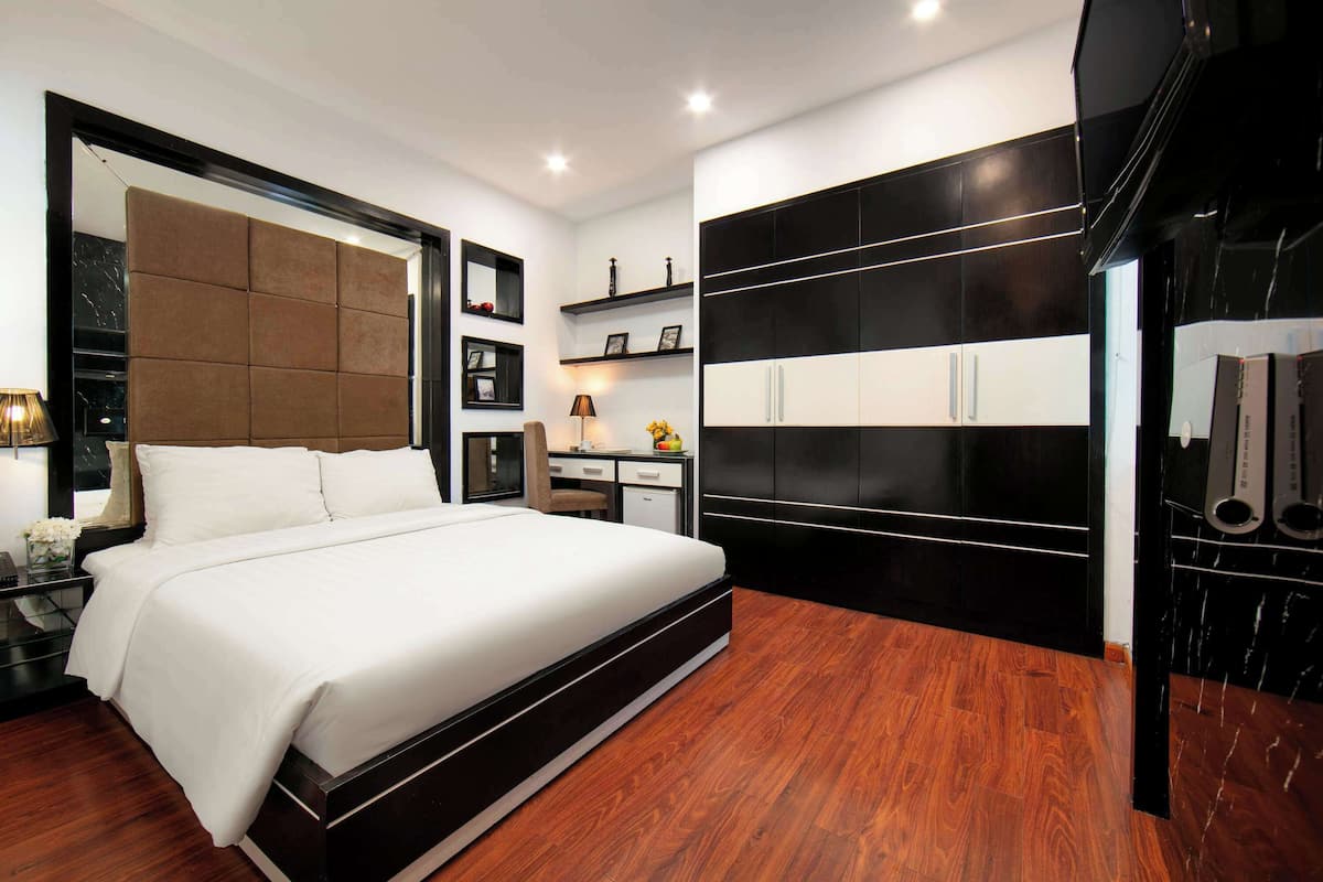 Quarto moderno com cama grande, guarda-roupa e escrivaninha com cadeira.