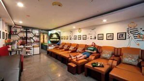 A spa area with leather sofas, a reception desk, and a wall with framed pictures and a logo. - THE SILK BOUTIQUE HOTEL & SPA (Hanoi)