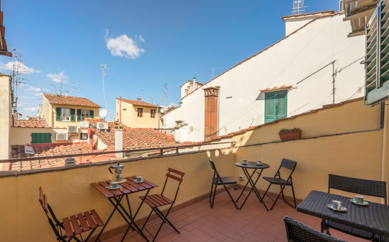 Un balcón con mobiliario exterior y vistas a edificios cercanos.