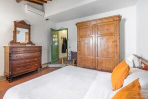 A bedroom with a wooden dresser, a large wardrobe, a bed with white bedding, and a chair. - Wine Apartments Florence Lambrusco (Firenze)