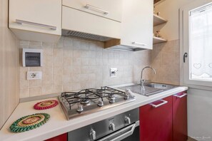 A kitchen with a gas stove, a sink, and red cabinets.