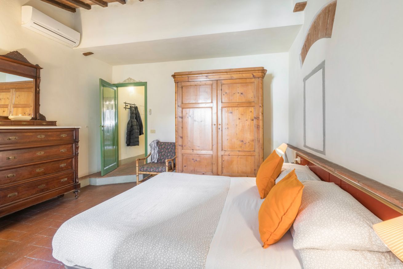 A bedroom with a bed, dresser, wardrobe, and a mirror.