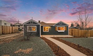 A two-story house with a dark exterior, a small front porch, and a well-maintained lawn.