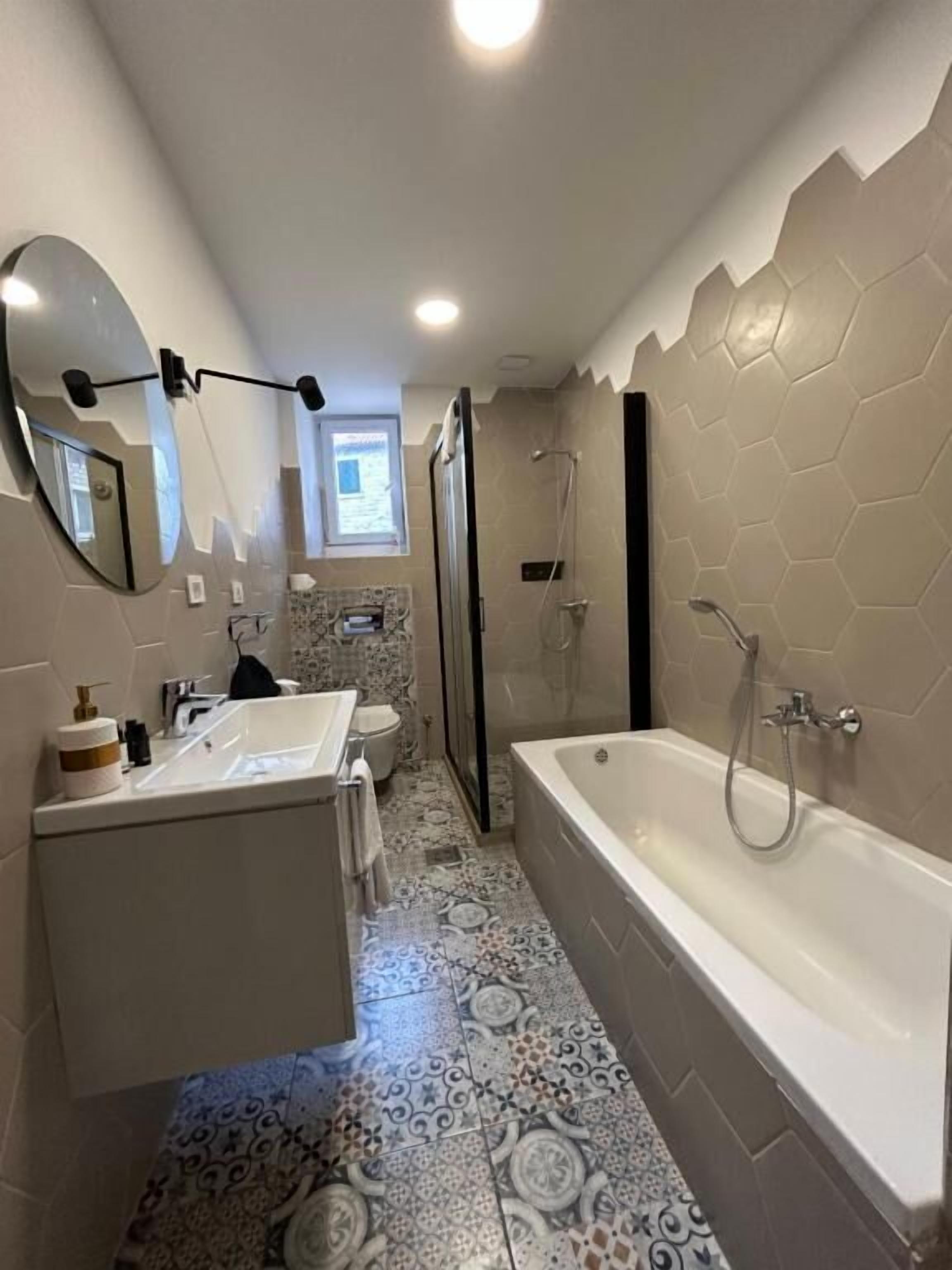 A modern bathroom with a large bathtub, a shower, and a toilet.