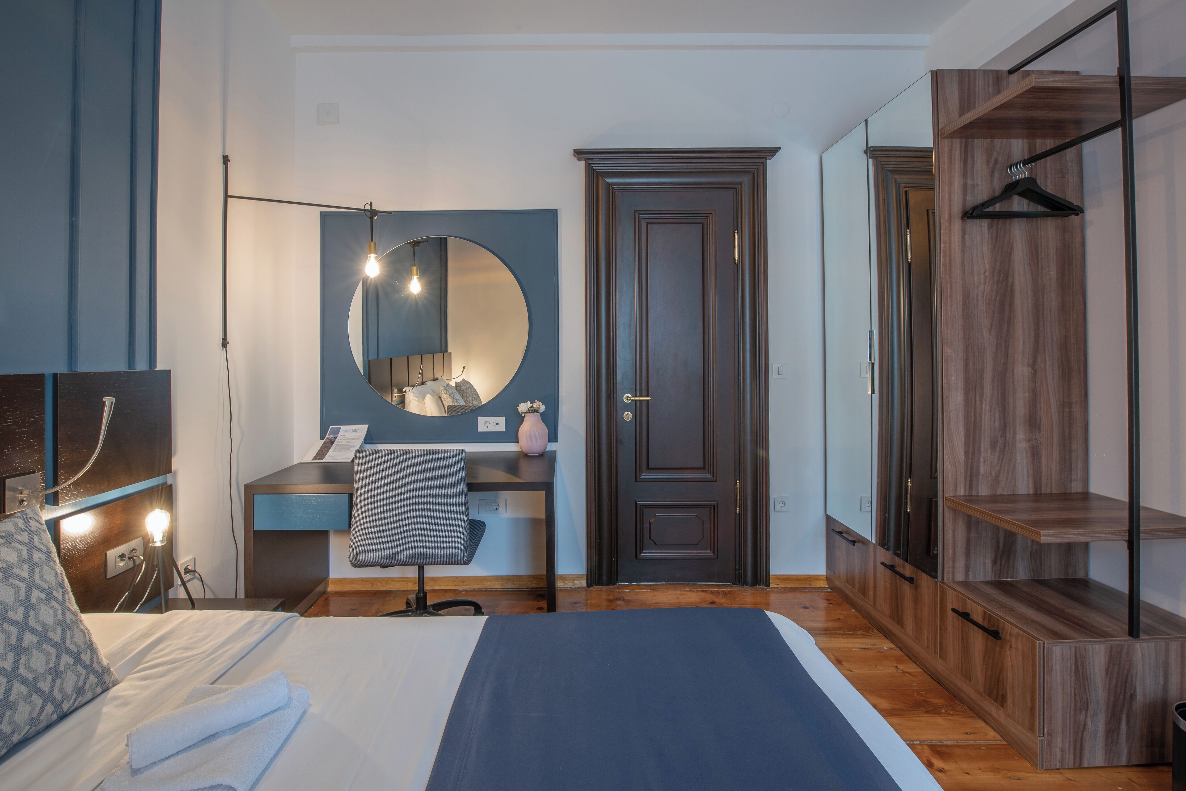 A modern bedroom with a bed, desk, chair, and wardrobe.