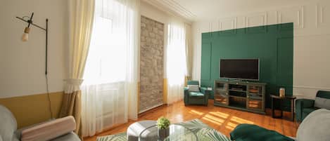 Una sala de estar moderna con una pared de acento de piedra, un televisor de pantalla plana y una pared de acento verde.