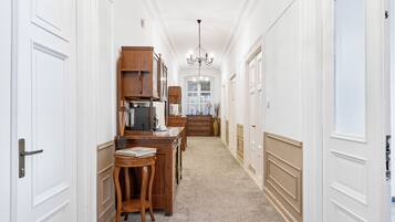 A hallway with a wooden desk, chairs, and a chandelier.
