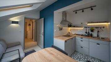A compact kitchen with a wooden table, a built-in oven, and a hanging pot rack.