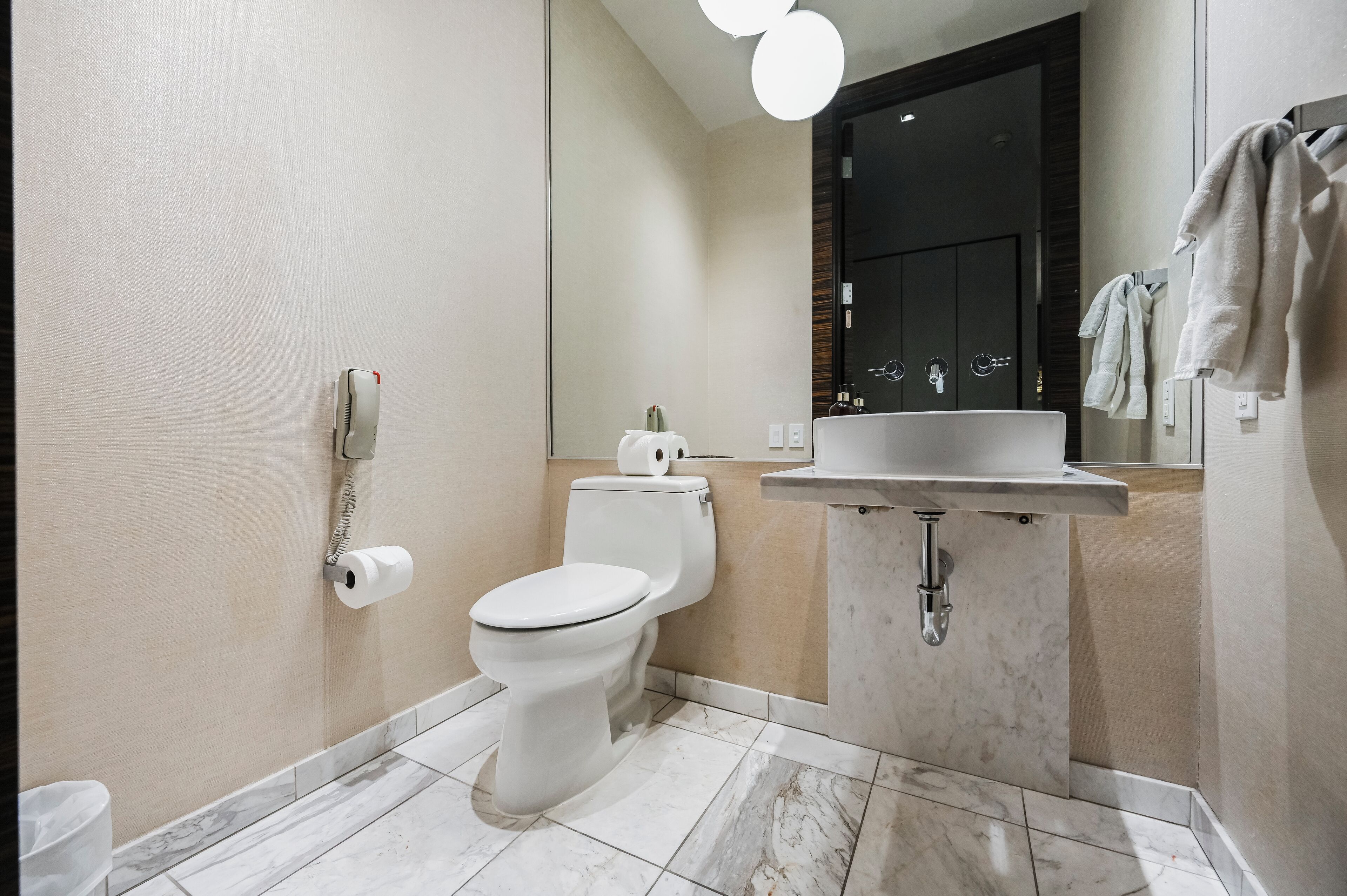 A modern bathroom with a toilet, sink, and towel rack.