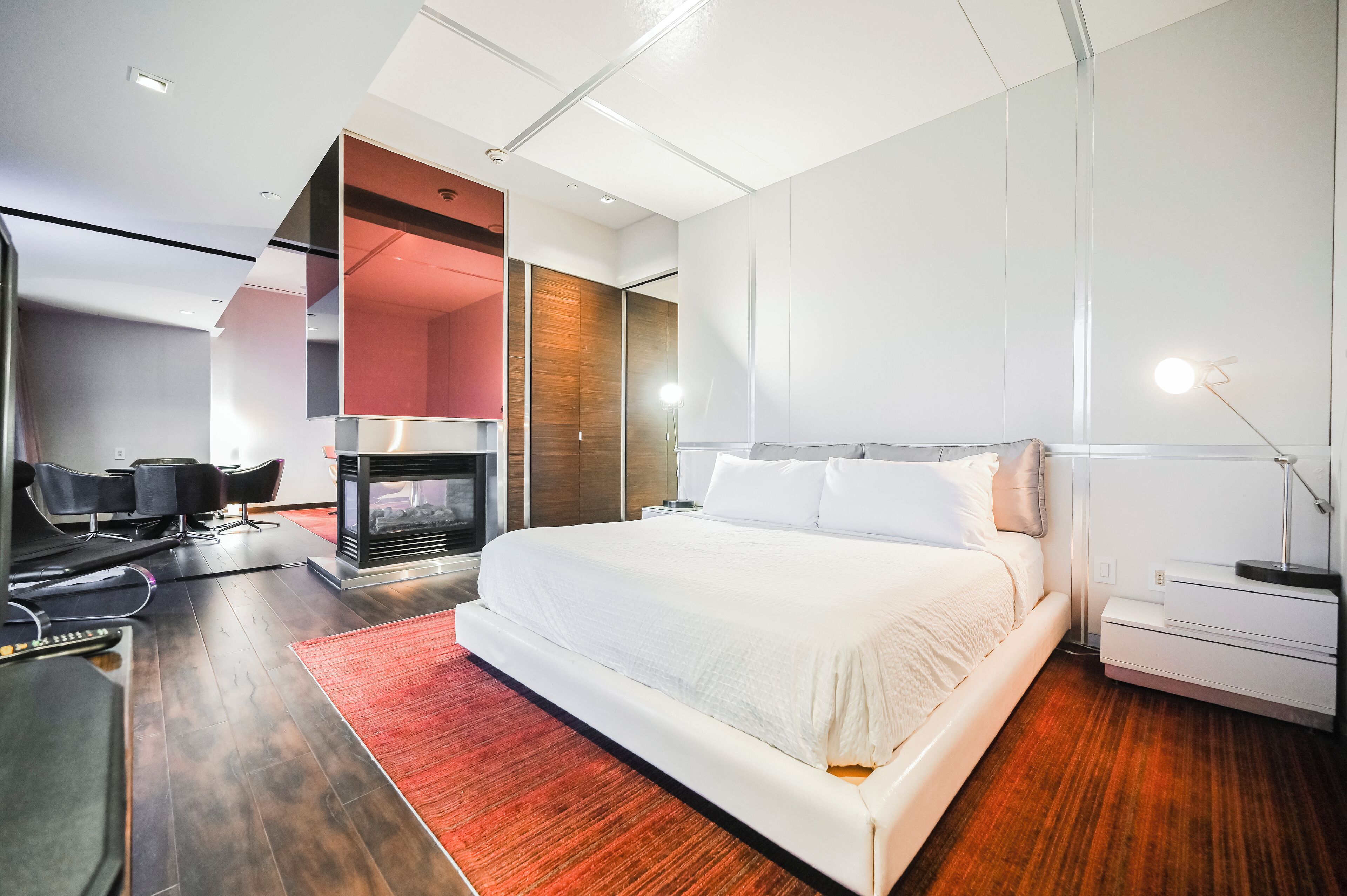 Ein modernes Hotelzimmer mit einem großen Bett, einer Sitzecke mit Stühlen, einem Fernseher und einem Kamin.